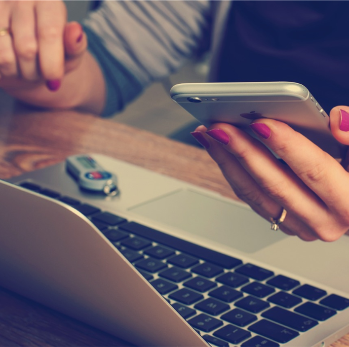 Image of woman working on laptop receiving mobile notification