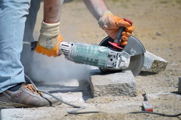 Worker using a power tool cutting a granite block